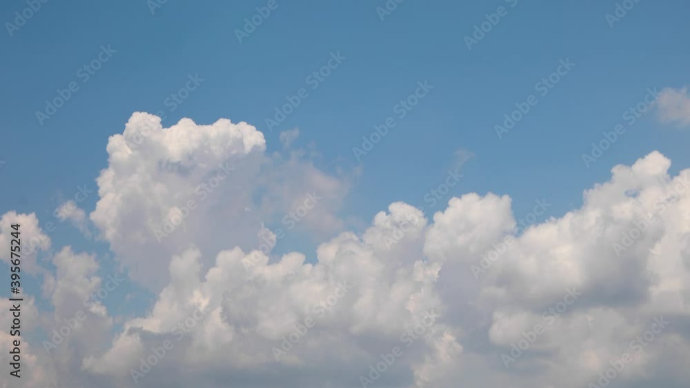 Swelling white clouds rise up, rolling in time lapse fashion over a vivid blue sky on a partly cloudy day in this one minute video with a looping fade at the end.
