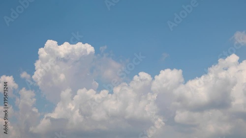 Swelling white clouds rise up, rolling in time lapse fashion over a vivid blue sky on a partly cloudy day in this one minute video with a looping fade at the end.