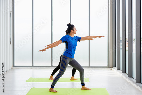 Fototapeta Naklejka Na Ścianę i Meble -  Two Asian women sporty attractive people practicing yoga lesson together, working out at the fitness GYM, Young and senior female exercising do yoga in yoga classes, sport healthy lifestyle