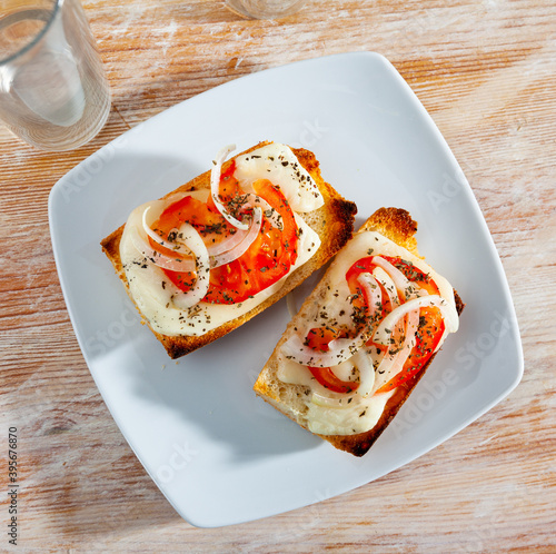 Bruschetta with cheese, slice of onion, tomato and spices