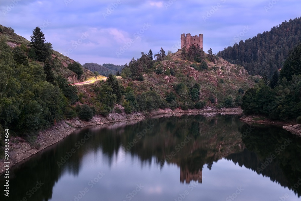 Medieval castle on hill above calm lake and reflections. Cantal. Auvergne. France Medieval castle on hill above calm lake and reflections. Cantal. Auvergne. France