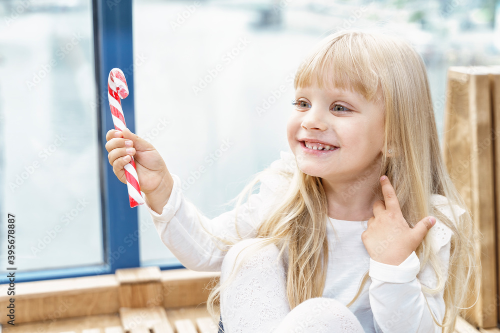 beautiful emotional blonde girl eating a candy cane and happy