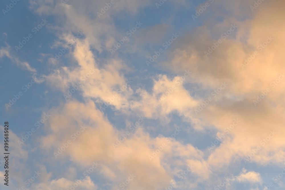 Colorful blue sky and clouds highlighted by setting sun, as a nature background
