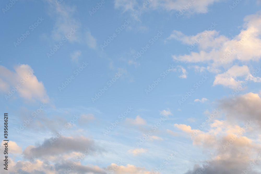 Colorful blue sky and clouds highlighted by setting sun, as a nature background
