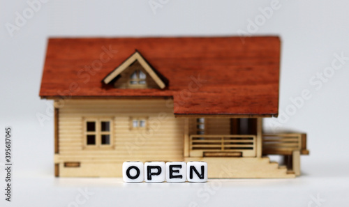 Close-up on a 'OPEN' and a miniature house. Concepts about restaurants that are starting to reopen. 