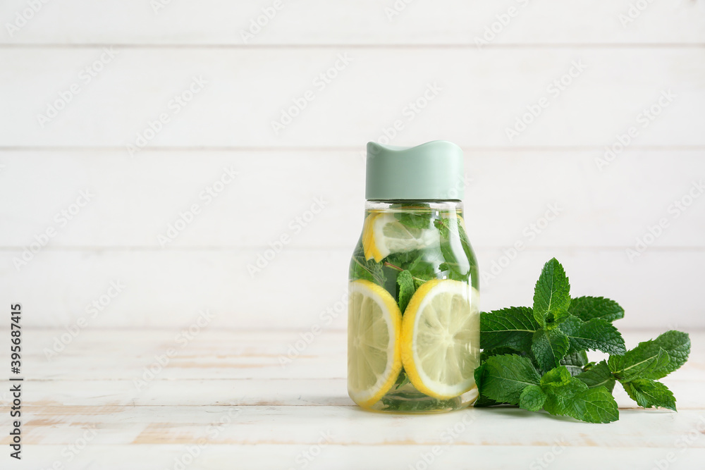 Bottle of water with fresh lemon and mint on light background Bottle of water with fresh lemon and mint on light background