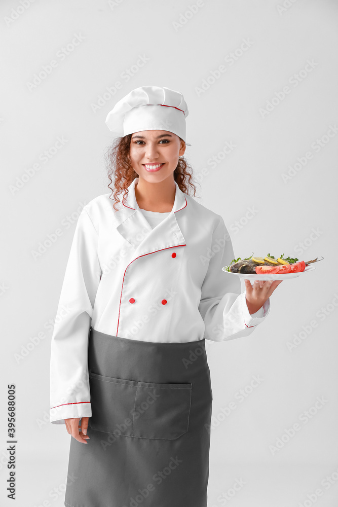 Young African-American female chef on light background