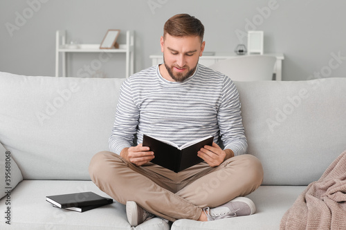 Young man reading book at home