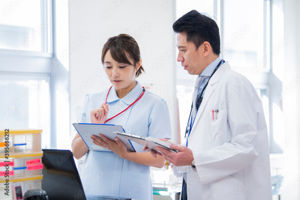 ナースステーションで笑顔で会話をする医師と看護師 ナースステーションで笑顔で会話をする医師と看護師