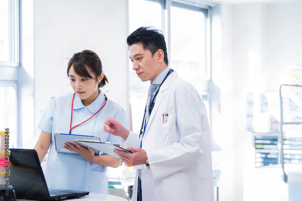 ナースステーションで笑顔で会話をする医師と看護師 アップ ナースステーションで笑顔で会話をする医師と看護師 アップ