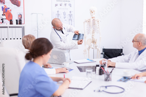 Expert doctor holding radiography during medical seminar for medical staff in conference room. Clinic therapist talking with colleagues about disease, medicine professional