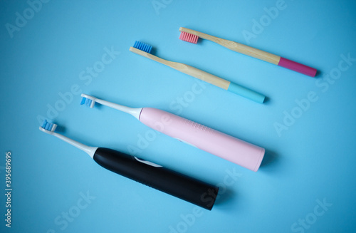 ultrasonic electric and bamboo toothbrushes on a blue background