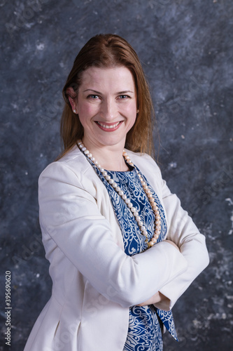 Cheerful middle aged woman in blue dress and white jacket photo