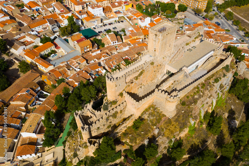 Aerial view of Almansa Castle, medieval fortification on stone hill surrounded by residential areas of city on sunny fall day, Albacete, Spain..
