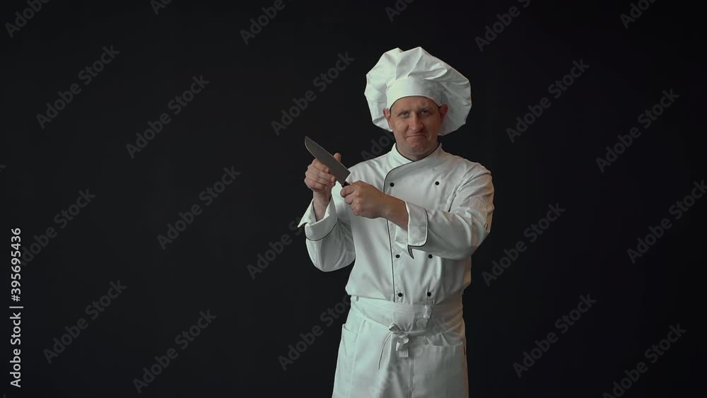 Male chef checking the quality of a large sharp kitchen knife. Copy space on black background. Male chef checking the quality of a large sharp kitchen knife. Copy space on black background.