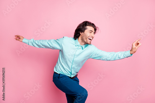 Photo of young multiethnic man happy excited fly plane hands look empty space isolated over pink color background