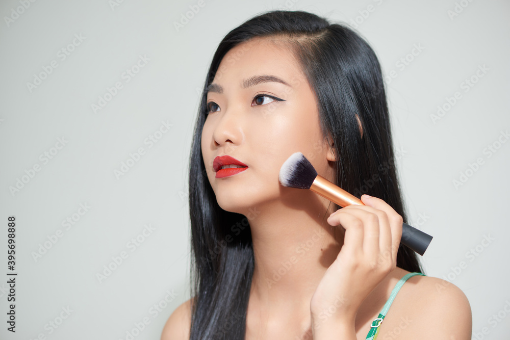 portrait of beautiful asian woman smiling while applying blush on isolated on white background portrait of beautiful asian woman smiling while applying blush on isolated on white background