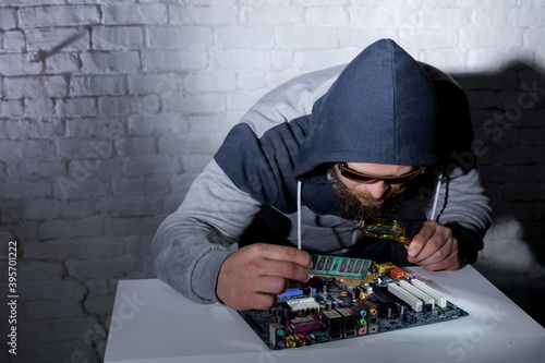 Bearded hacker in sunglasses and hoodie cracking the hardware