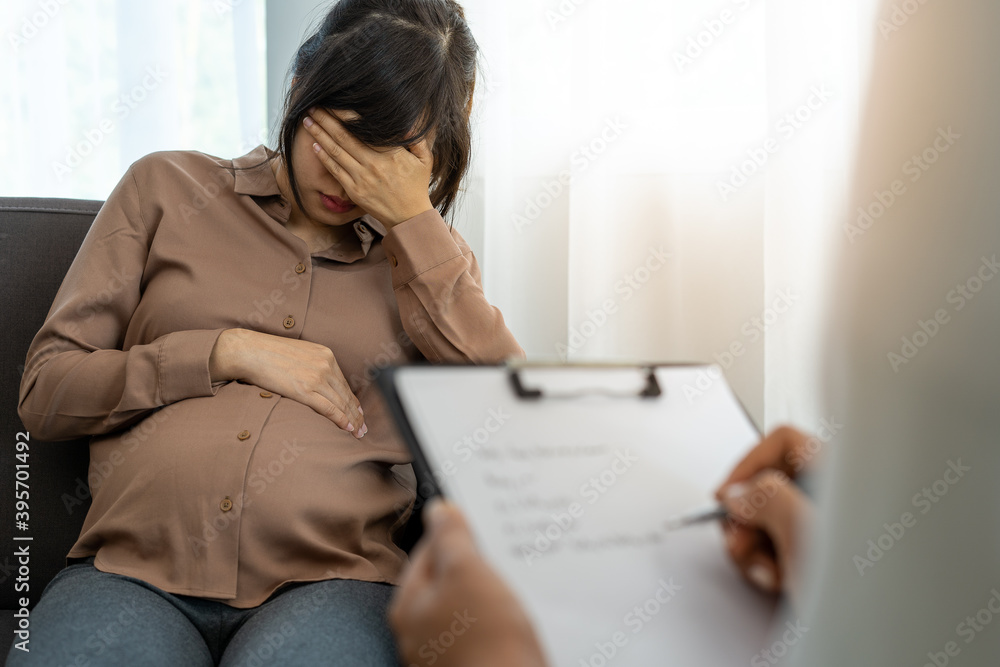 The pregnant mother is discussing depression symptoms during pregnancy with a specialist doctor or psychiatrist. The future mom is unhappy, worried, and stressed. Mental health concept - obrazy, fototapety, plakaty 