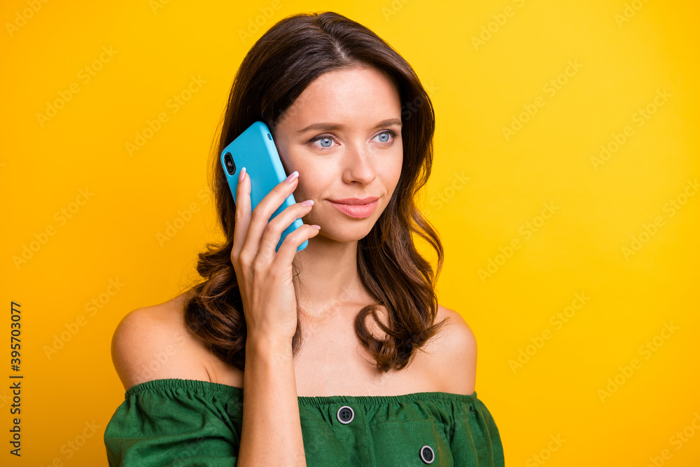 Photo of serious calm young woman hold talk smartphone look empty space isolated on yellow color background