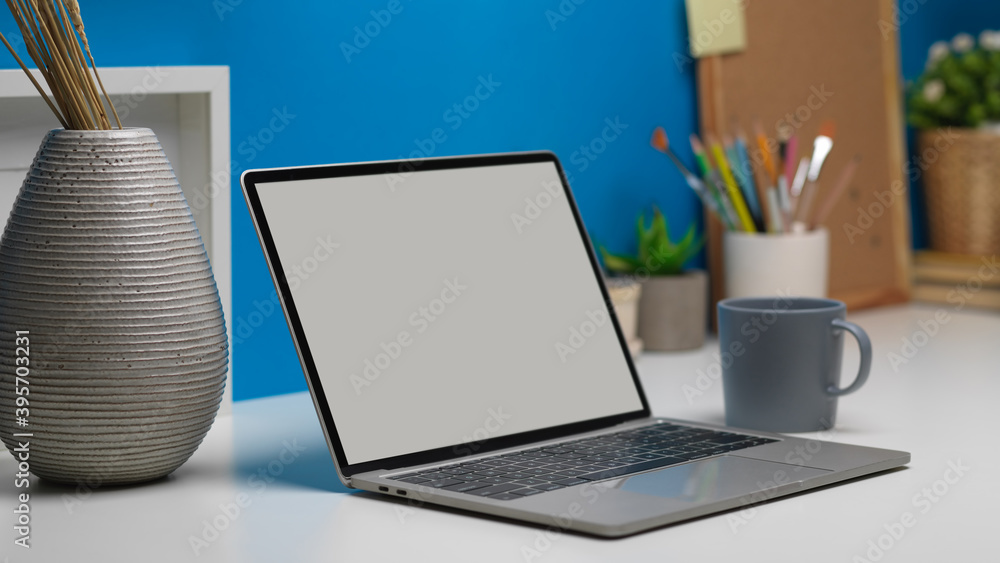 Side view of worktable with laptop, stationery, decorations in home office room Side view of worktable with laptop, stationery, decorations in home office room