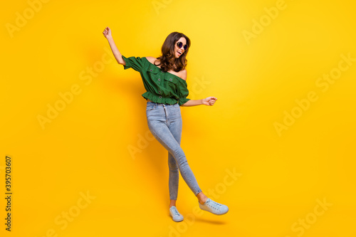 Full body photo of careless pretty joyful young woman raise hands dancer wear glasses isolated on yellow color background