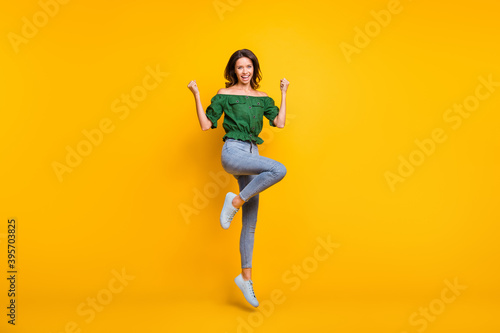 Full body photo of victorious happy woman raise fists yeah jump up wear shoes isolated on shine yellow color background