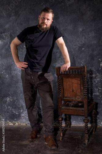 Mature bearded man dressed in t-shirt sitting on chair