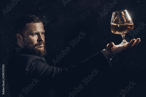 Solid confident bearded man in suit with glass of whisky
