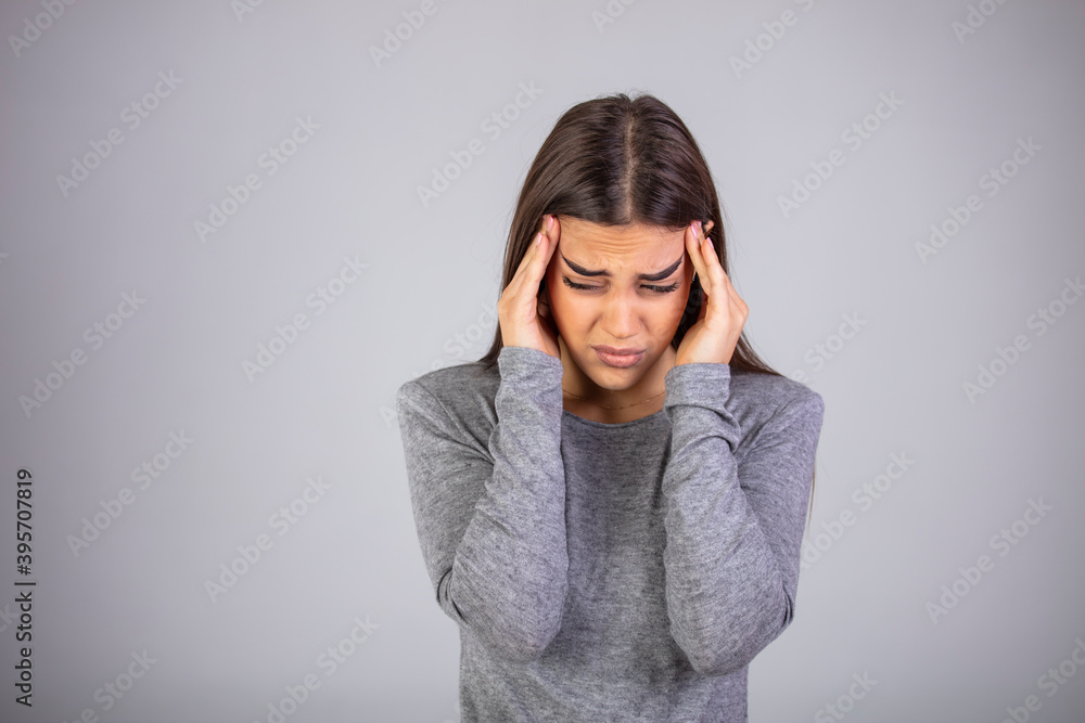 Woman holding hands to her temples having terrible headache. Studio shot on grey wall. Woman has a terrible headache, isolated on white wall. Studio shot Woman holding hands to her temples having terrible headache. Studio shot on grey wall. Woman has a terrible headache, isolated on white wall. Studio shot