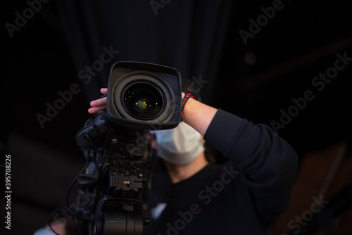 masked cameraman is filming a television show in the studio.