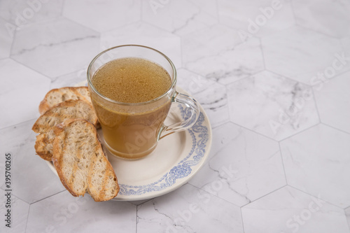A Cup of hot broth for lunch with toasted white bread on a light background. Copy space