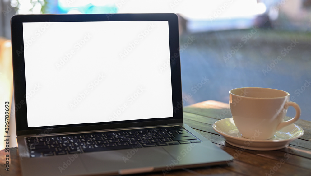 Close - up shot of A laptop mockup blank screen and a coffee mug on the table in the cafe. Close - up shot of A laptop mockup blank screen and a coffee mug on the table in the cafe.