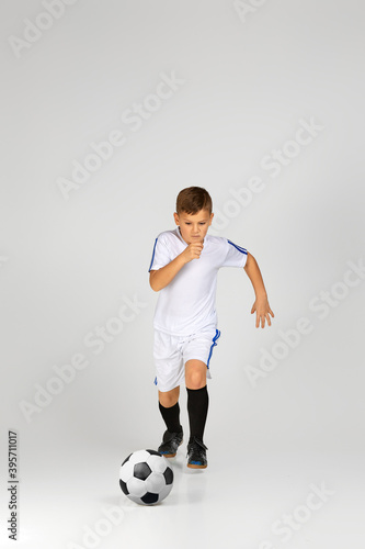 little child boy in uniform playing with soccer ball over studio background. © producer