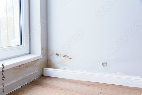 Fallen off plaster from a room wall  due to flooding. Crumbling plaster  in a room near window.