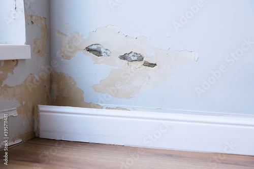 Fallen off plaster from a room wall  due to flooding. Crumbling plaster  in a room near window.