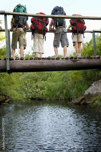 Teenagers Carrying Backpacks On Bridge Looking Down