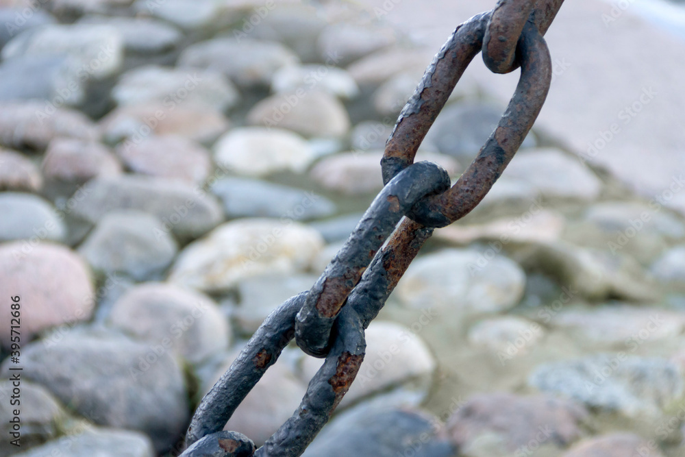 Old forged rusty chain with peeling paint on the background of paving stones. Old forged rusty chain with peeling paint on the background of paving stones.