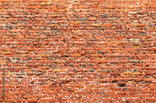 Obraz na plátne Brick wall made of old crumbling red bricks falling out.