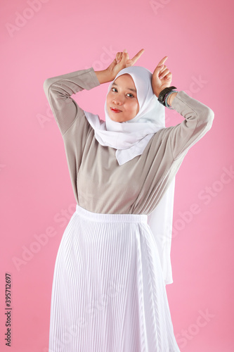 Fashion portrait of young beautiful asian muslim woman with wearing hijab isolated on pink background. © faishalabdula