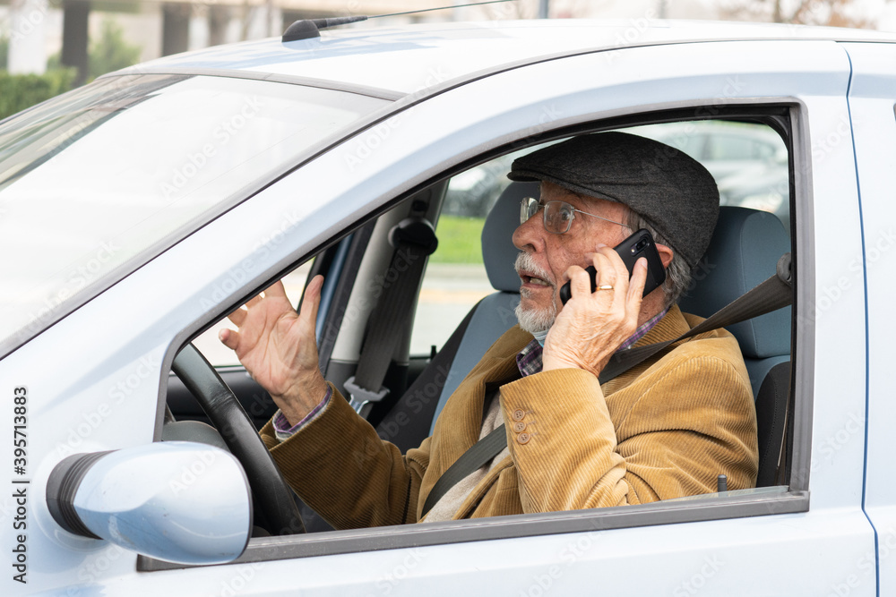 Old man drives his car while talking on mobile phone. Dangerous driving on the road Old man drives his car while talking on mobile phone. Dangerous driving on the road