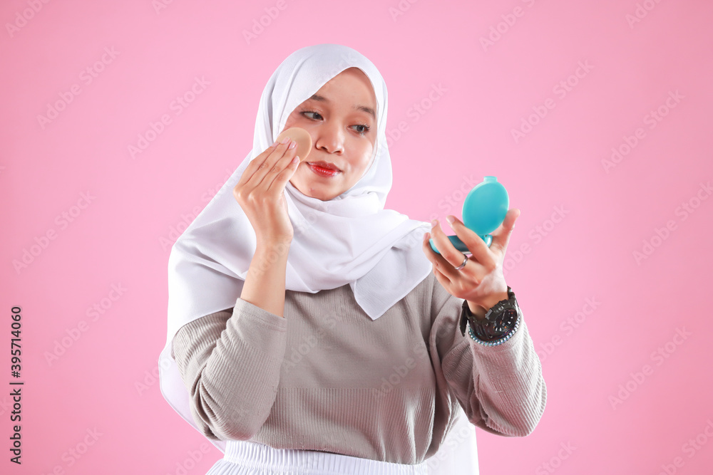 Portrait of beautiful asian woman applying powder puff at cheek makeup of cosmetic isolated on pink background. Portrait of beautiful asian woman applying powder puff at cheek makeup of cosmetic isolated on pink background.