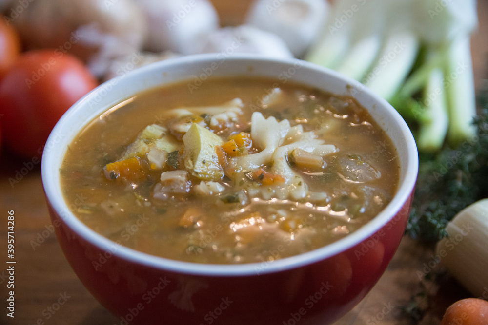 Minestrone soup, a typical thick vegetables soup, originally from Italy, served in a red bowl with Farfalle Pasta. Minestrone soup, a typical thick vegetables soup, originally from Italy, served in a red bowl with Farfalle Pasta.