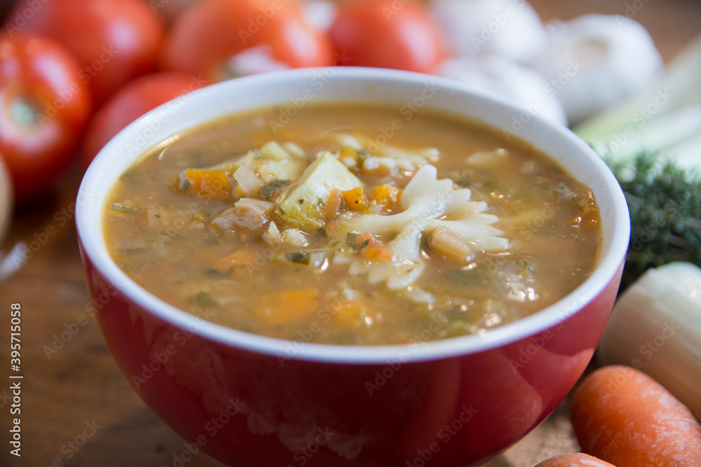 Minestrone soup, a typical thick vegetables soup, originally from Italy, served in a red bowl with Farfalle Pasta. Minestrone soup, a typical thick vegetables soup, originally from Italy, served in a red bowl with Farfalle Pasta.