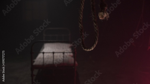 scary noose gallows for execution swings in dark against background of white metall bed in dark hospital or hangar sinister. Horror movie concept. bed with old mattress for corpse after hanging. © Vit