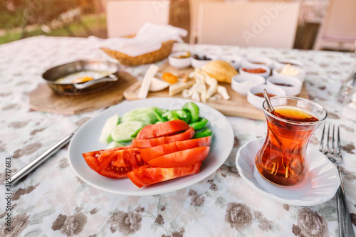 Traditional Turkish glass with strong tea  vegetables and other snacks for a rich middle eastern Breakfast in the outdoor restaurant