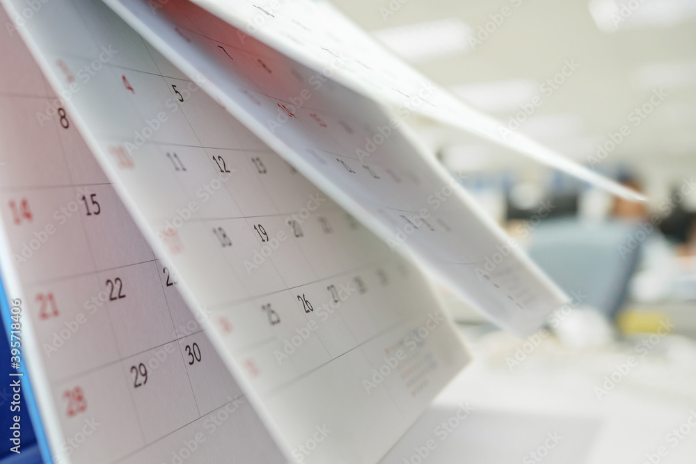 Calendar page flipping sheet on table with blurred office interior background business schedule planning appointment meeting concept Calendar page flipping sheet on table with blurred office interior background business schedule planning appointment meeting concept