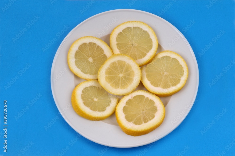 Rondelles de citron dans une assiette sur fond bleu Rondelles de citron dans une assiette sur fond bleu