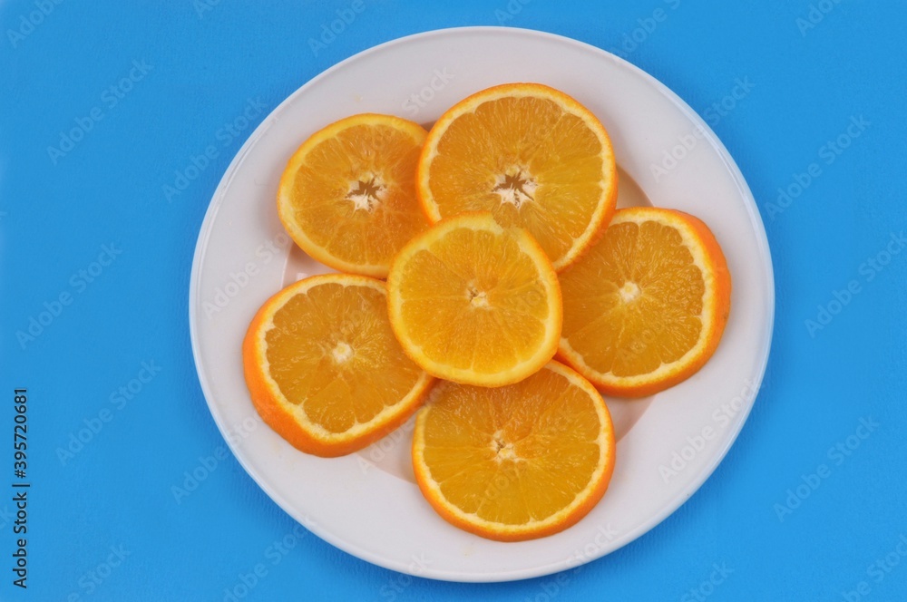 Rondelles d'orange dans une assiette sur fond bleu Rondelles d'orange dans une assiette sur fond bleu