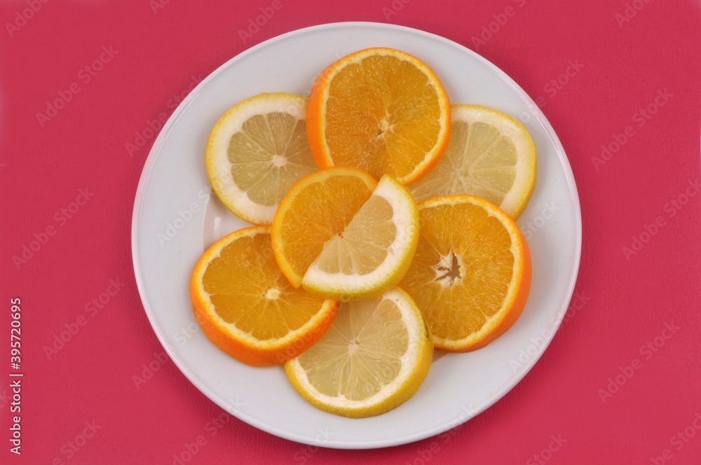 Rondelles d'orange et de citron dans une assiette sur fond rouge Rondelles d'orange et de citron dans une assiette sur fond rouge